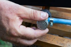 man's hand opens or closes gas valve on gas pipe, closeup